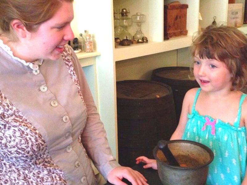 A costumed interpreter talks to a girl at Living History Farms