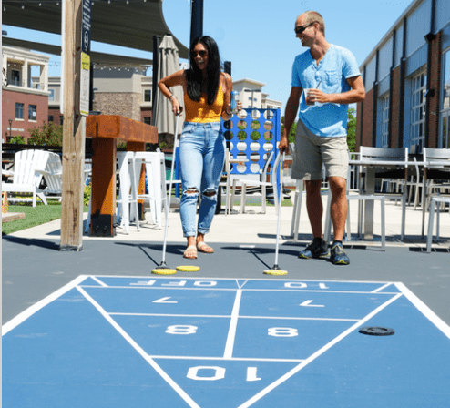 A couple plays shuffleboard outdoors at Smash Park in West Des Moines