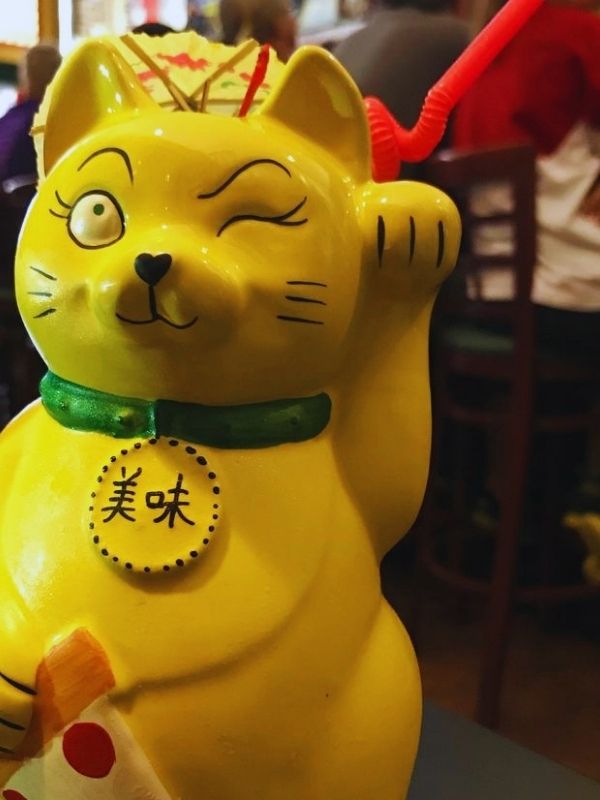 Up-close photo of a waving cat cup at Fong's Pizza