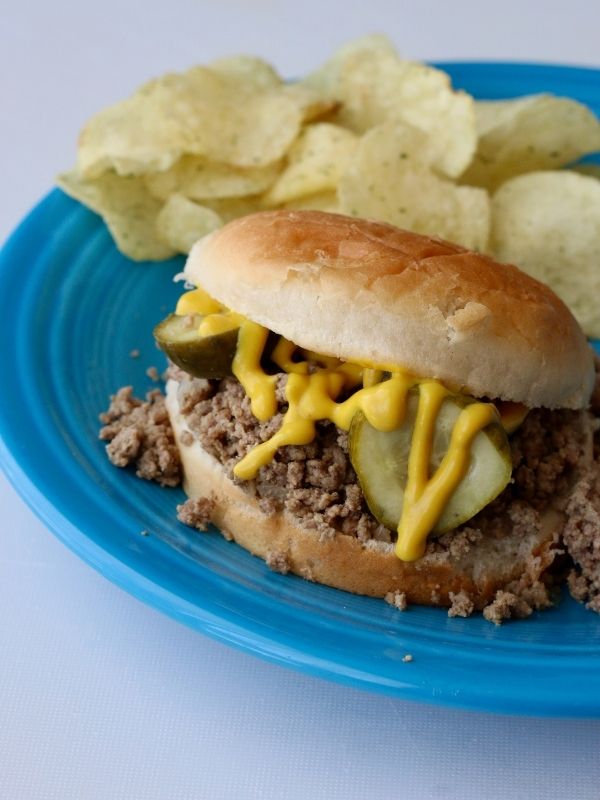 Up-close photo of a loose meat sandwich with pickles and mustard 