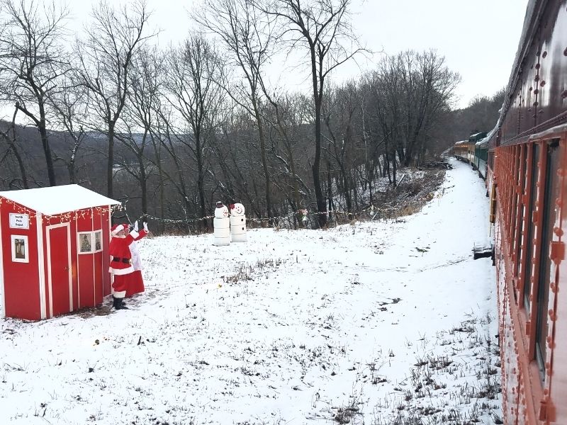 Santa and Mrs. Claus waving to passerby on the Boone & Scenic Valley Railroad