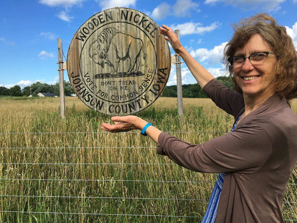 A woman poses with the world's largest wooden nickel, found in Iowa