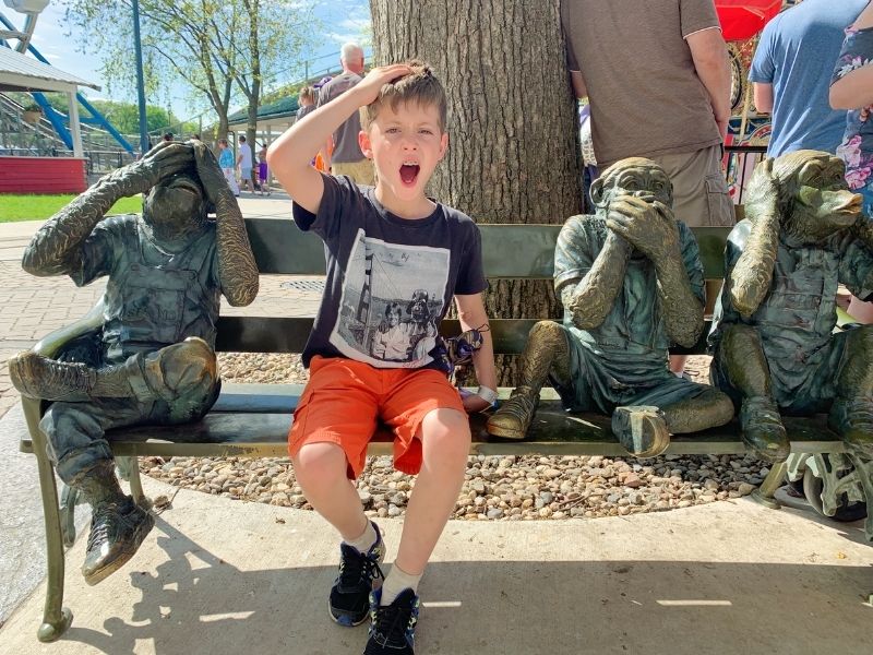 Boy sitting with monkey statues at Arnolds Park Amusement Park