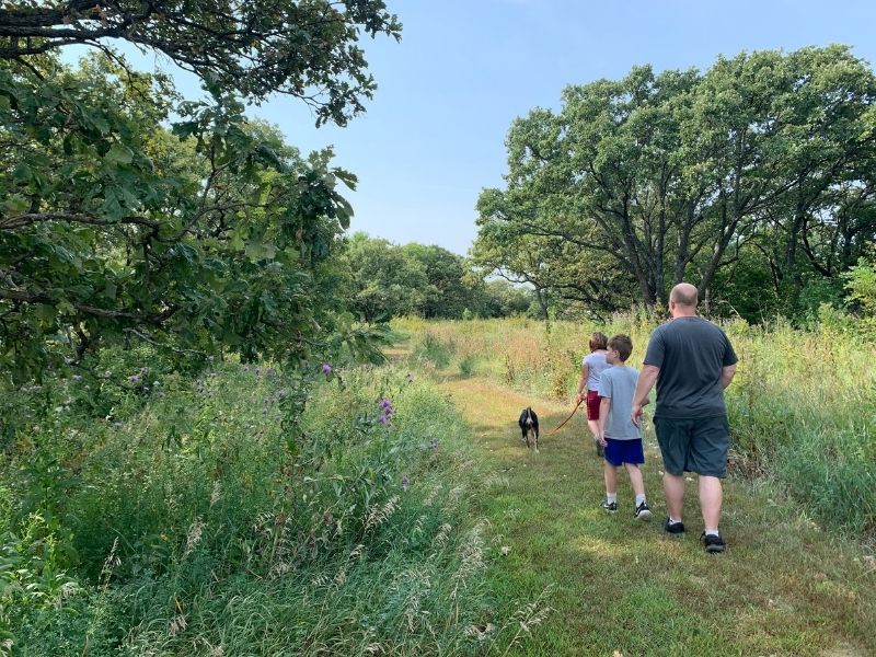 Family walking a dog along the prairie at West Oak Forest in southwest Iowa