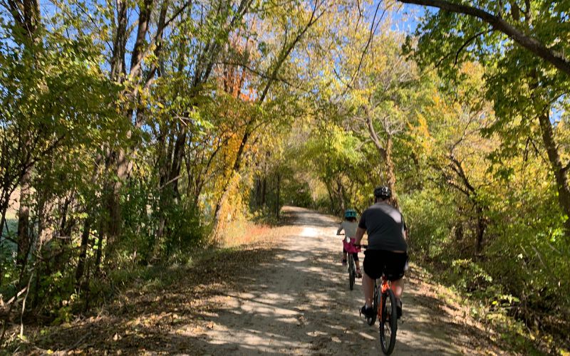 A father and daughter bike along the Wabash Trace Trail in the fall