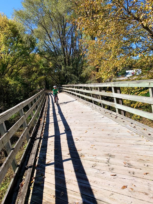 A child biking across a bridge on the Wabash Trace Trail in Iowa