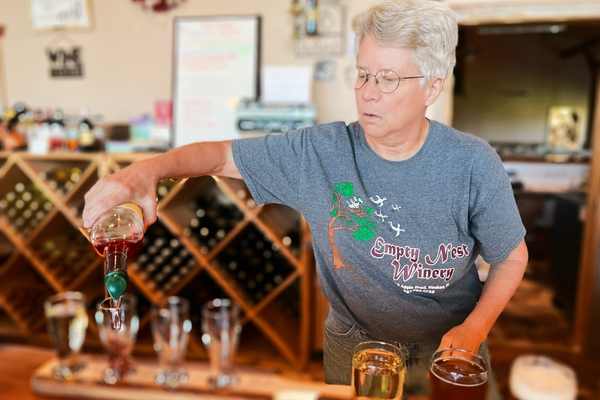A woman pours wine into a flight glass at Empty Nest Winery in Waukon, Iowa