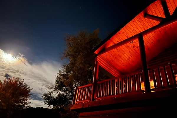 A cabin lit up at night at Upper Iowa Resort & Rental in Dorchester, Iowa, with a full moon in the sky