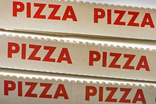 A stack of pizza boxes with PIZZA in red letters