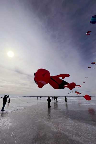 People stand on the frozen lake to look at kites during Color The Wind in Clear Lake, Iowa