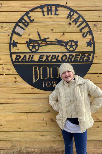 A girl poses in front of the Rail Explorers sign in Boone