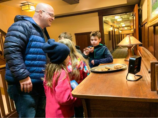 Kids and a dad grab a chocolate cookie from a tray in the hall at Hotel Pattee