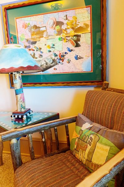 A chair and side table with a lamp, all fitting the travel theme of the room at Hotel Pattee in Iowa