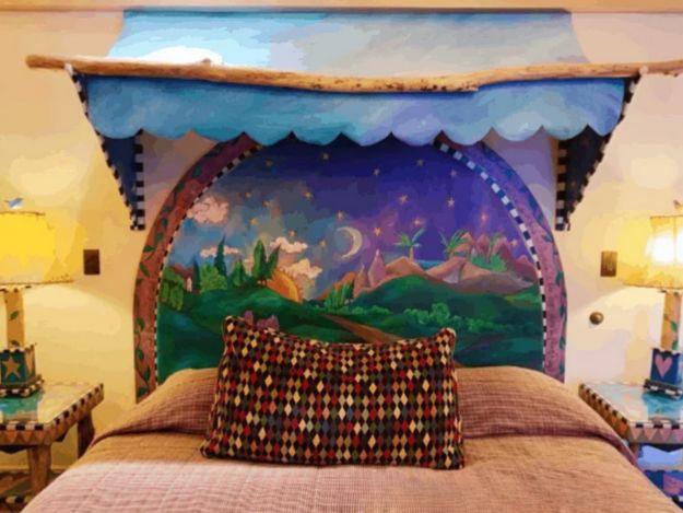 A bed with a decorated headboard in a travel themed suite at Hotel Pattee