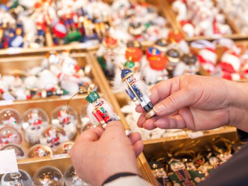 A shopper holds two small nutcrackers at a stall at a holiday market