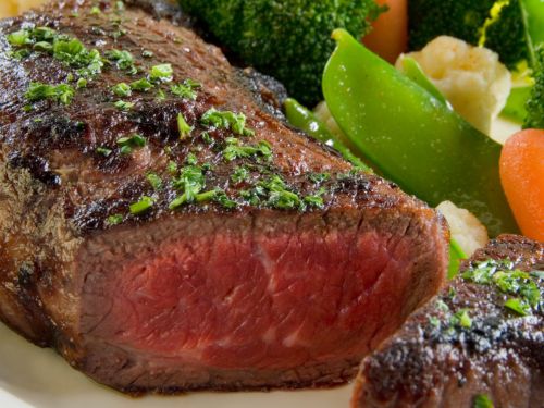 Medium-rare steak cut with steamed veggies on a plate