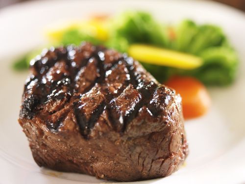 A close-up photo of a filet with colorful vegetables behind it