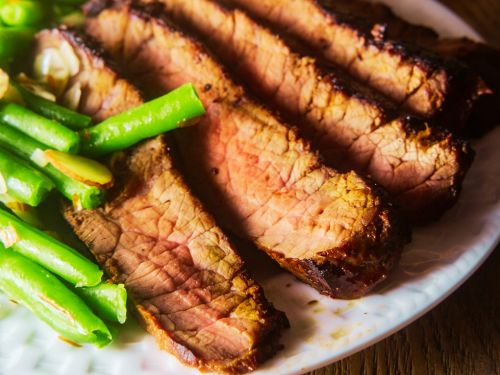 Slices of steak with green beans on the side