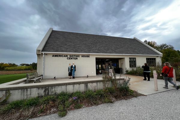 The exterior of the American Gothic House Visitor Center, with a statue of the two figures from the painting standing in front