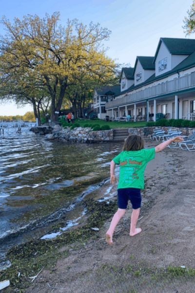 A girl runs barefoot on a sand beach by Crescent Beach Family Resort in Okoboji