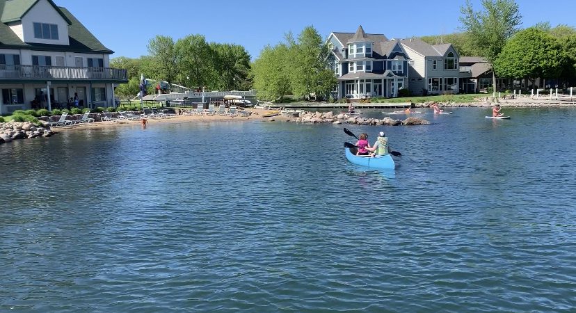 People in a canoe and on standup paddle boards float on the water near Milford, Iowa, a part of Okoboji