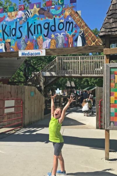 A kid raises her hands at the entrance of Kids Kingdom at Blank Park Zoo in Des Moines, Iowa